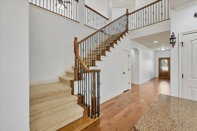 foyer featuring hardwood / wood-style flooring, ornamental molding, and a towering ceiling