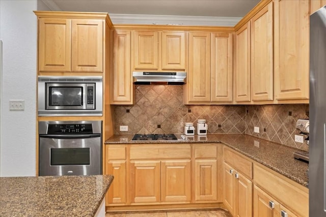 kitchen featuring tasteful backsplash, light brown cabinetry, appliances with stainless steel finishes, dark stone counters, and under cabinet range hood