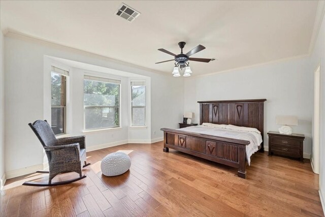 bedroom with ceiling fan, ornamental molding, and light wood-type flooring