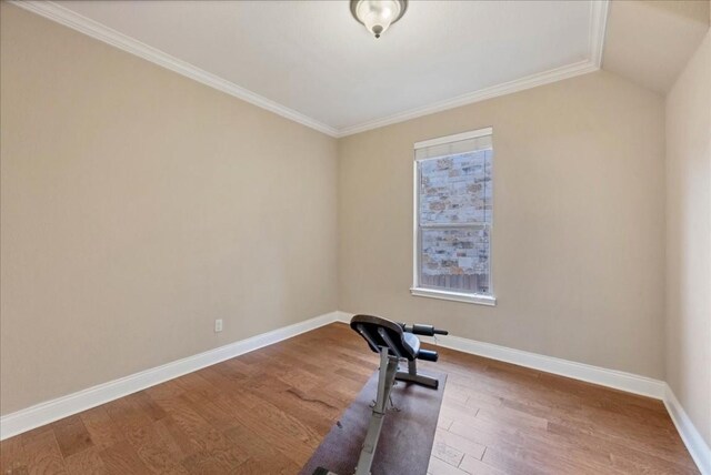 exercise room featuring lofted ceiling, crown molding, and wood-type flooring