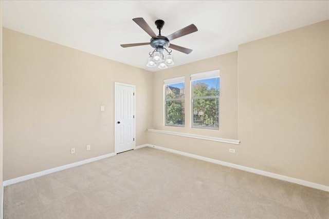 empty room with a ceiling fan, light colored carpet, and baseboards