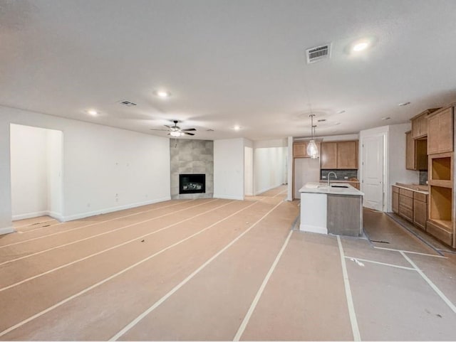 unfurnished living room with ceiling fan and a tile fireplace