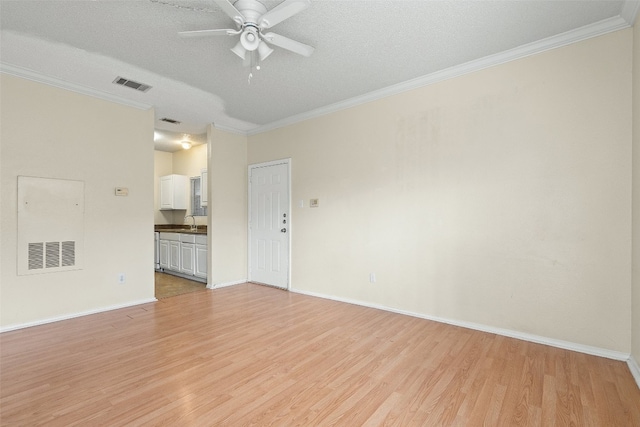 spare room featuring light wood-type flooring, a textured ceiling, crown molding, and ceiling fan