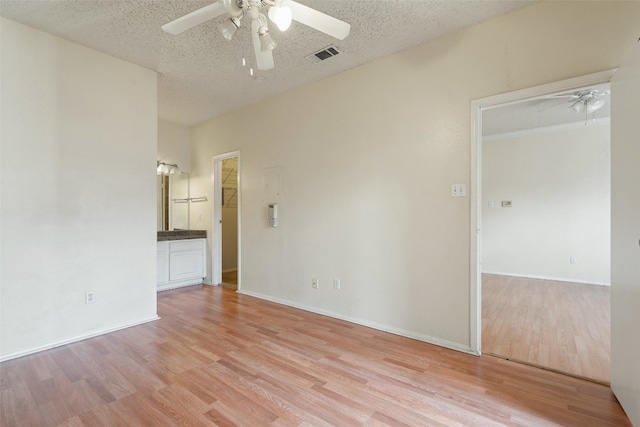 unfurnished room with a textured ceiling, ceiling fan, and light hardwood / wood-style flooring