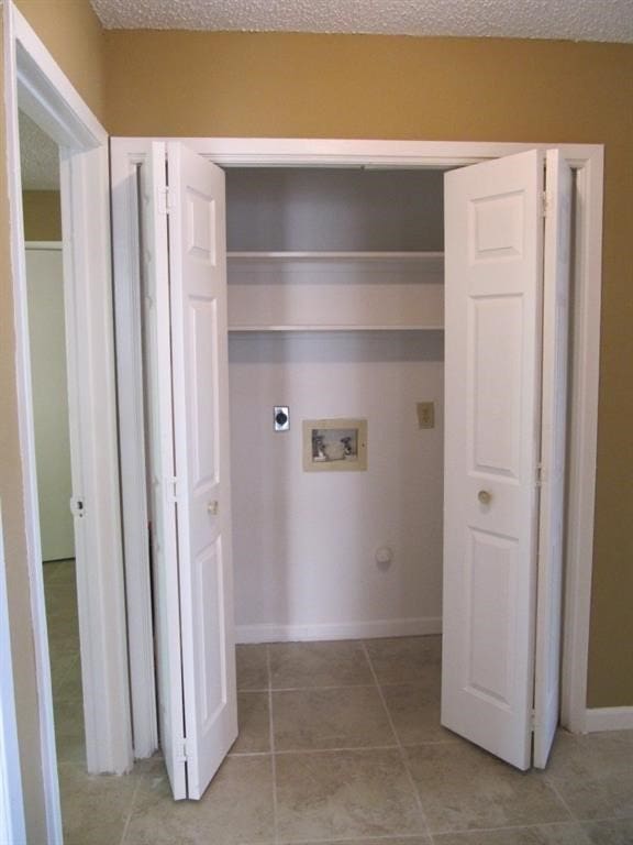 laundry room featuring hookup for an electric dryer, light tile patterned floors, a textured ceiling, and hookup for a washing machine