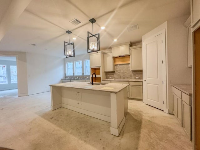 kitchen with sink, hanging light fixtures, light stone countertops, a center island with sink, and decorative backsplash