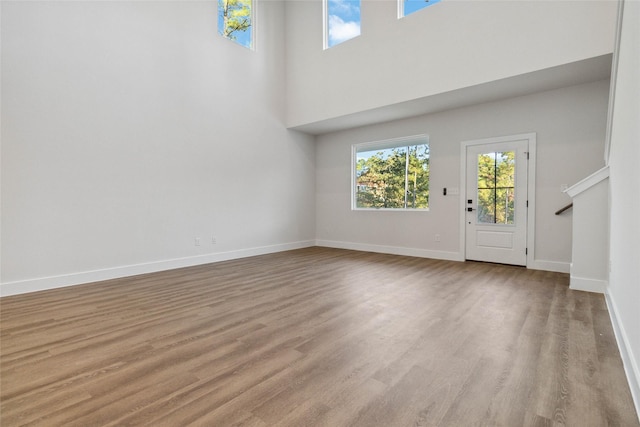 unfurnished living room featuring light hardwood / wood-style flooring and a high ceiling