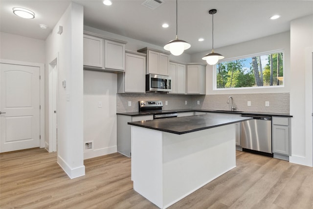 kitchen featuring stainless steel appliances, gray cabinets, sink, and a kitchen island