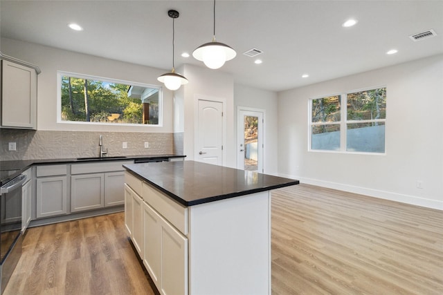 kitchen with sink, gray cabinets, backsplash, light hardwood / wood-style floors, and decorative light fixtures