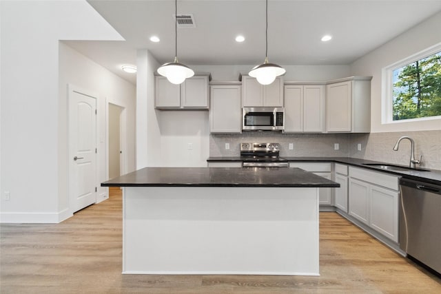 kitchen featuring appliances with stainless steel finishes, a center island, and decorative light fixtures