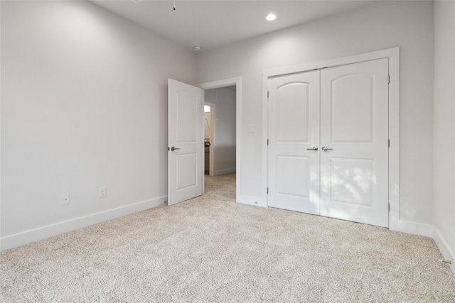 unfurnished bedroom with light carpet and a closet