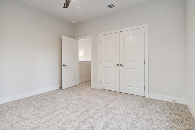 unfurnished bedroom with ceiling fan, light colored carpet, and a closet