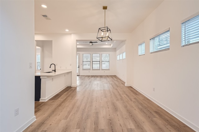 interior space with sink, ceiling fan with notable chandelier, and light hardwood / wood-style flooring