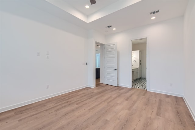 unfurnished bedroom with ensuite bath, light hardwood / wood-style floors, and ceiling fan