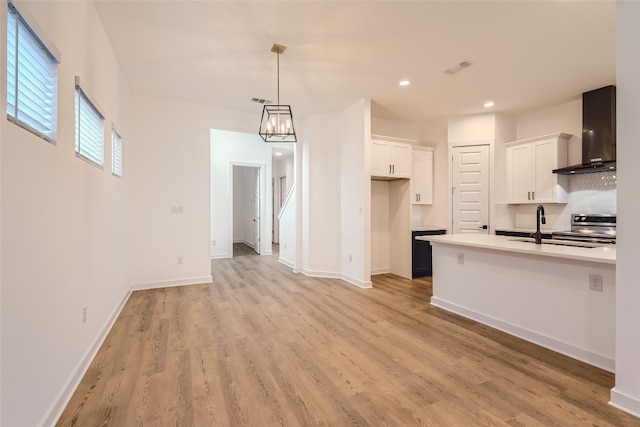 kitchen with white cabinetry, wall chimney range hood, pendant lighting, stainless steel electric range oven, and light hardwood / wood-style floors