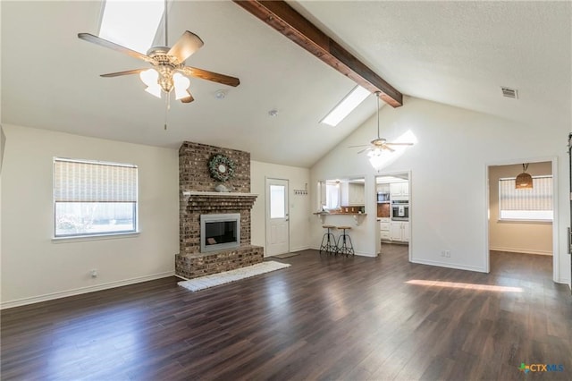 unfurnished living room featuring dark hardwood / wood-style flooring, ceiling fan, plenty of natural light, and a skylight