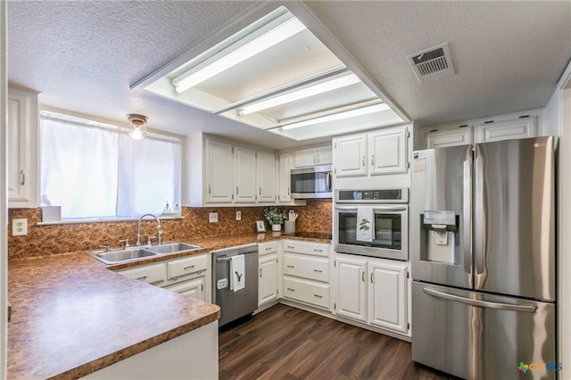 kitchen with white cabinets, appliances with stainless steel finishes, a textured ceiling, and sink