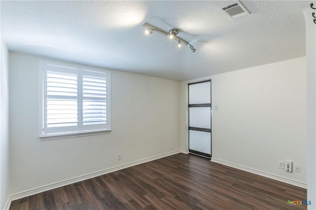 empty room with a textured ceiling and dark hardwood / wood-style floors