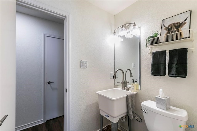 bathroom featuring toilet, sink, and wood-type flooring