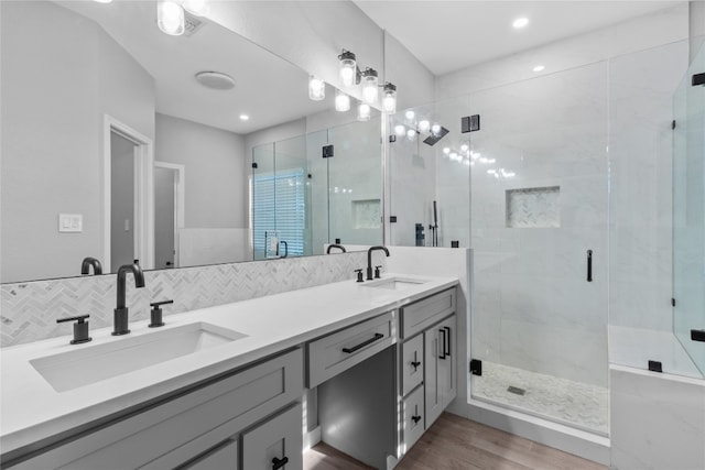 bathroom featuring decorative backsplash, vanity, hardwood / wood-style floors, and a shower with shower door