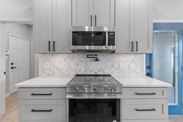 kitchen with white cabinetry, light wood-type flooring, decorative backsplash, and stainless steel appliances