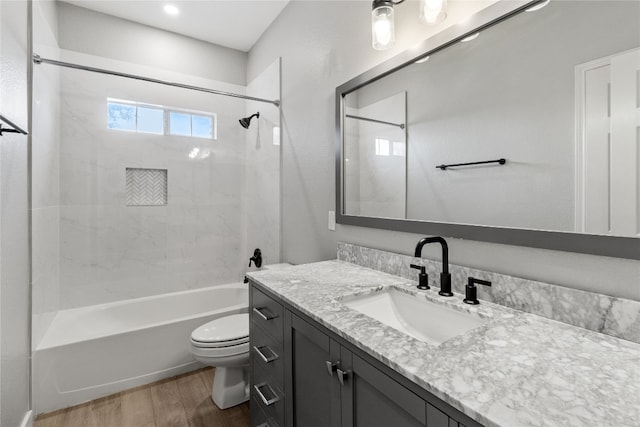 full bathroom with hardwood / wood-style floors, vanity, toilet, and tiled shower / bath