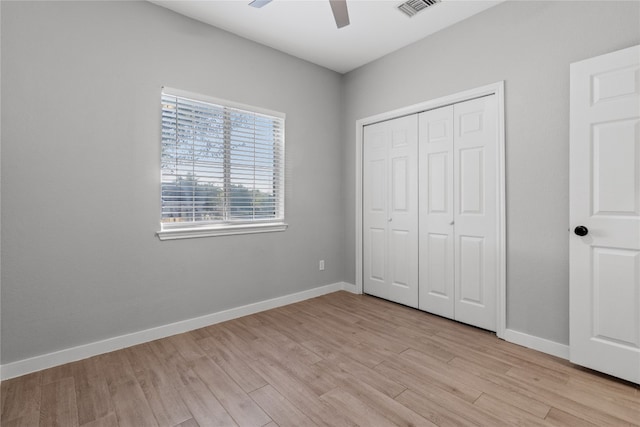 unfurnished bedroom with light hardwood / wood-style flooring, ceiling fan, and a closet