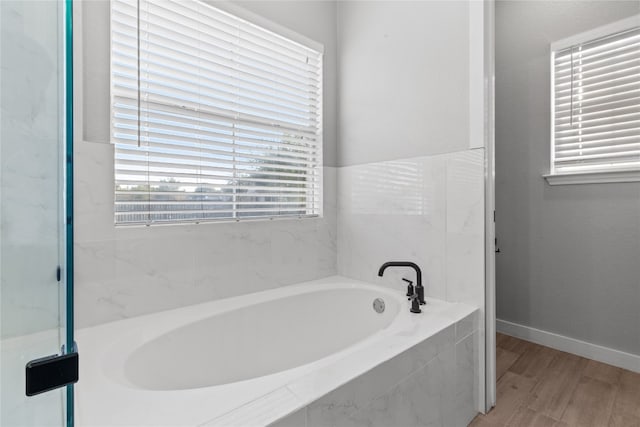 bathroom with hardwood / wood-style floors and tiled bath