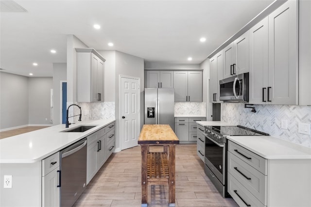 kitchen with backsplash, sink, light hardwood / wood-style flooring, and appliances with stainless steel finishes