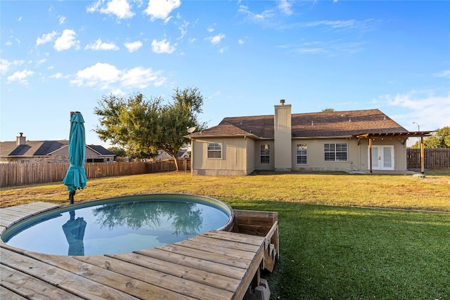 view of swimming pool with a lawn, french doors, and a deck