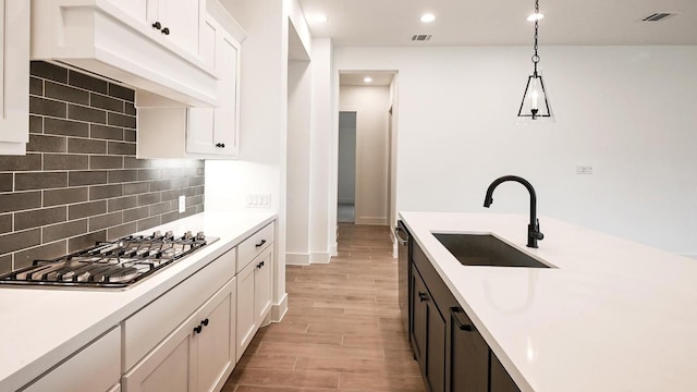 kitchen with stainless steel gas cooktop, light countertops, a sink, and custom exhaust hood