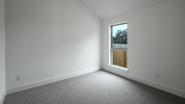 spare room with vaulted ceiling, carpet floors, and baseboards