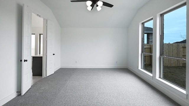 carpeted spare room with lofted ceiling, a ceiling fan, and baseboards