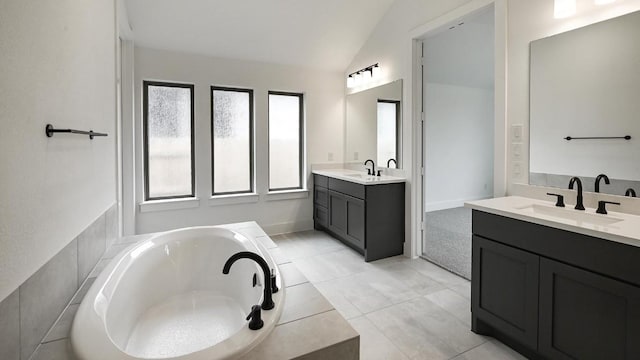 bathroom with vaulted ceiling, two vanities, a sink, and a garden tub