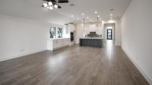 kitchen featuring open floor plan, dark wood-style flooring, backsplash, and white cabinets