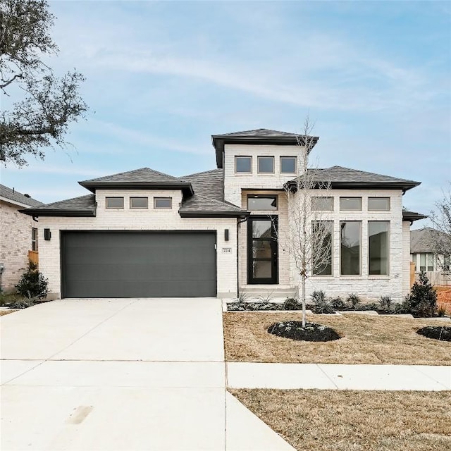 prairie-style house featuring a garage, concrete driveway, and brick siding