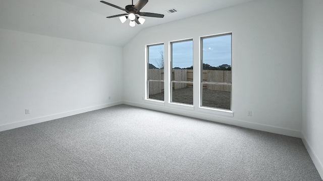 carpeted spare room featuring a ceiling fan, visible vents, vaulted ceiling, and baseboards