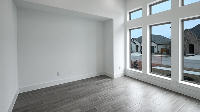 spare room with dark wood-type flooring and baseboards