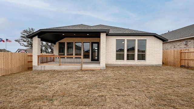 back of property with a shingled roof, a fenced backyard, a yard, a patio area, and brick siding