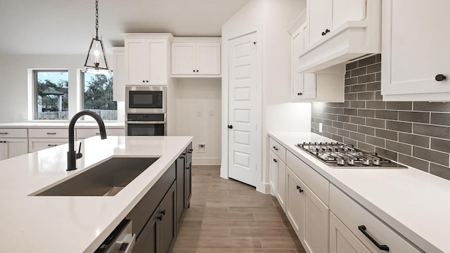 kitchen featuring light countertops, appliances with stainless steel finishes, a sink, and white cabinetry