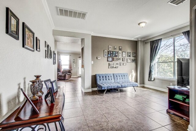 living room with tile patterned floors, ornamental molding, and plenty of natural light