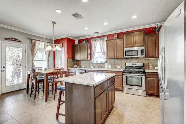 kitchen with stainless steel appliances, light tile patterned floors, pendant lighting, and a center island