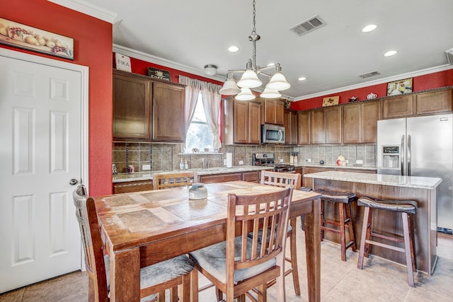 kitchen featuring a center island, hanging light fixtures, light tile patterned floors, crown molding, and appliances with stainless steel finishes