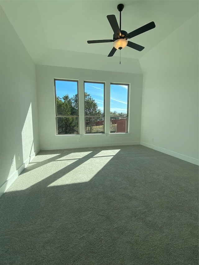 empty room featuring ceiling fan, vaulted ceiling, and carpet flooring