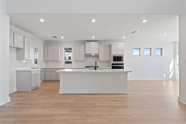 1515 Cardinal Ln, Round Rock, TX 78681 - kitchen featuring oven, under cabinet range hood, tasteful backsplash, stainless steel microwave, and recessed lighting