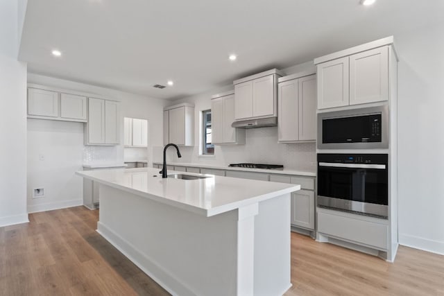 1515 Cardinal Ln, Round Rock, TX 78681 - kitchen with stainless steel appliances, a sink, an island with sink, light countertops, and backsplash