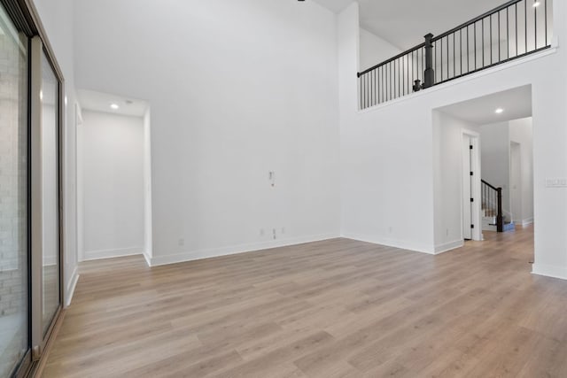 1515 Cardinal Ln, Round Rock, TX 78681 - unfurnished living room featuring a towering ceiling, stairway, light wood-style floors, baseboards, and recessed lighting