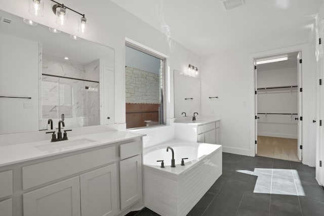 1515 Cardinal Ln, Round Rock, TX 78681 - full bath with a marble finish shower, two vanities, a garden tub, tile patterned flooring, and a spacious closet