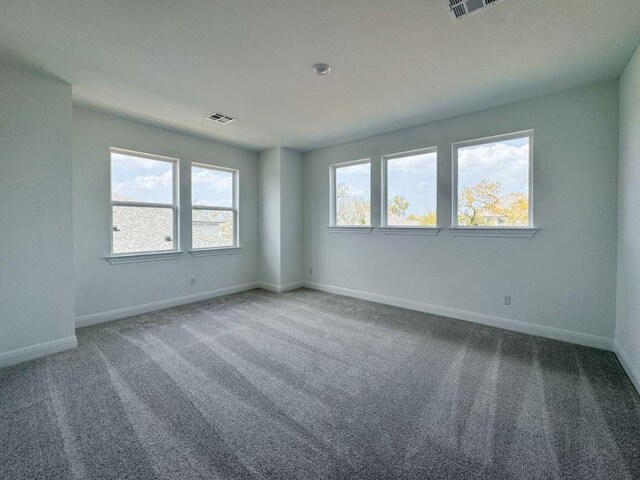 empty room with carpet, visible vents, and baseboards