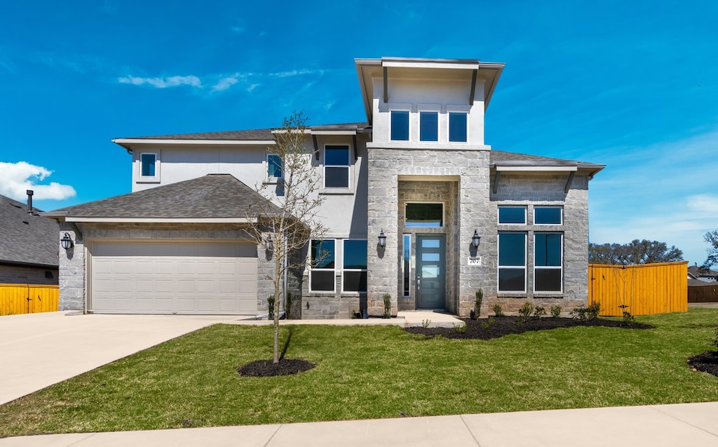 707 Jackson River Loop, Kyle, TX 78640 - prairie-style house with stone siding, an attached garage, concrete driveway, and a front lawn